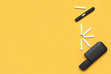 Modern electronic cigar and sticks on orange background