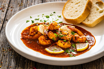 Louisiana style shrimp in hot sauce with bread on wooden table