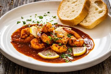 Louisiana style shrimp in hot sauce with bread on wooden table