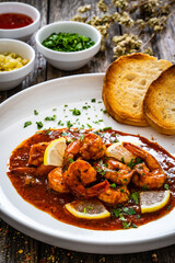 Louisiana style shrimp in hot sauce with bread on wooden table