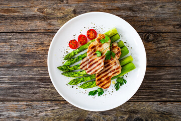 Grilled meat and asparagus on wooden table
