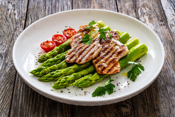 Grilled meat and asparagus on wooden table
