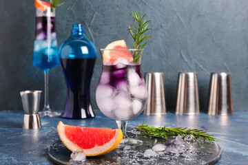 Glasses of gin and tonic with grapefruit and rosemary on grunge table near wall