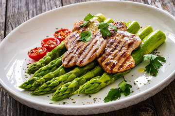 Grilled meat and asparagus on wooden table
