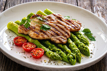 Grilled meat and asparagus on wooden table
