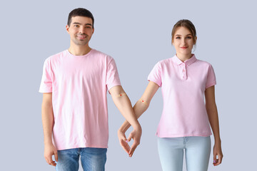 Young couple after donating blood holding hands on light background