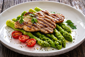 Grilled meat and asparagus on wooden table
