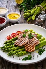 Grilled meat and asparagus on wooden table
