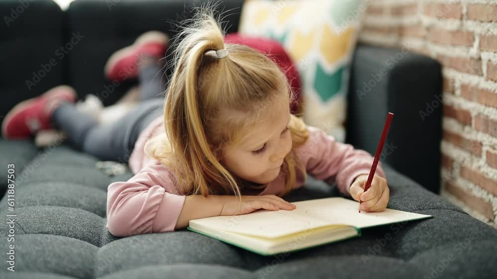 Sticker Adorable blonde girl preschool student lying on sofa drawing on notebook at home