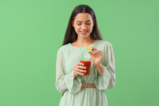 Young Woman With Glass Of Vegetable Juice And Lime On Green Background