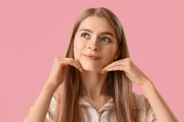 Obraz premium Young woman doing face building exercise on pink background, closeup