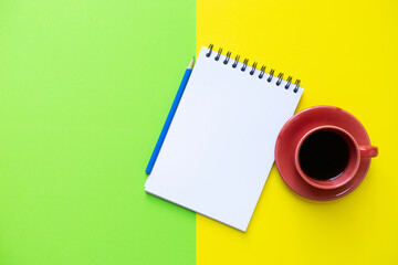 Coffee cup, note book on the yellow and green table background, creative at the office