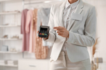 Female seller with payment terminal in boutique, closeup