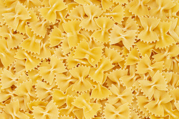 Dry uncooked farfalle pasta as a background. Flat lay.