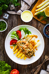 Seared chicken breast with white cooked asparagus and fresh vegetables on wooden table
