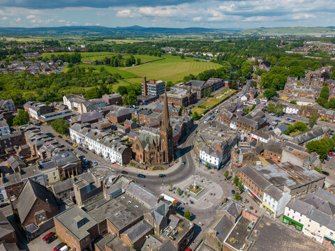 This aerial drone photo shows the town of Dumfries in the district of Dumfries and Galloway in Scotland. In the center of the town there is a large church on a small square. 