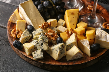 Plate with pieces of tasty cheese on table, closeup