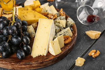 Plate with pieces of tasty cheese on dark wooden background, closeup