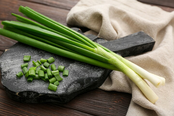 Wooden board with fresh cut green onion on table