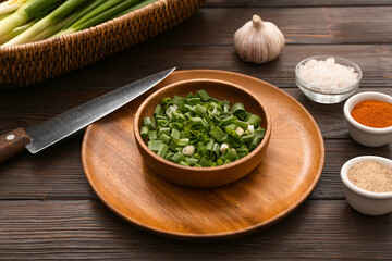 Bowl with fresh cut green onion on wooden background