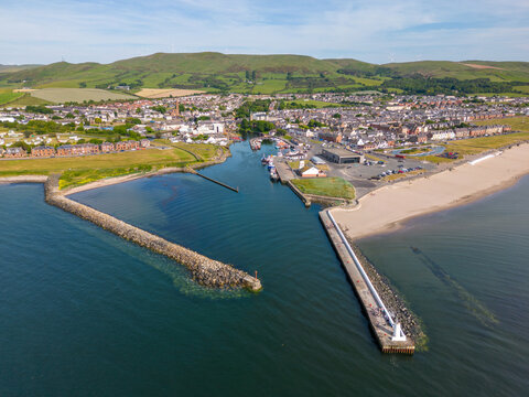 This aerial drone photo shows the entrance to the harbour of Girvan in Ayrshire in Scotland. There is a large pier with a small light house. 