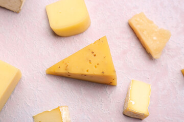 Pieces of tasty cheese on light background