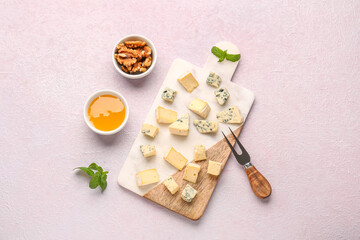Board with pieces of tasty cheese, nuts and honey on light background