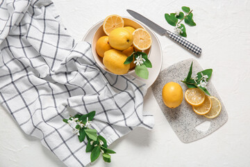 Bowl and board of lemons with blooming branches on white table