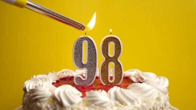 A candle in the form of the number 98, inserted into the holiday cake, is lit. Celebrating a birthday or a landmark event. The climax of the celebration.
