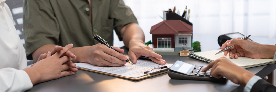Panorama view of married couple signing house loan contract with real estate agent. Client customer purchasing new home, sealing the deal with signatures after reviewing terms and agreements. Prodigy
