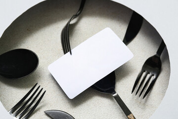 Composition with blank card and cutlery on light background, closeup