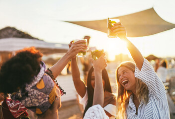 Multiracial happy friends cheering and drinking mojitos at beach party - Focus on left hand holding...