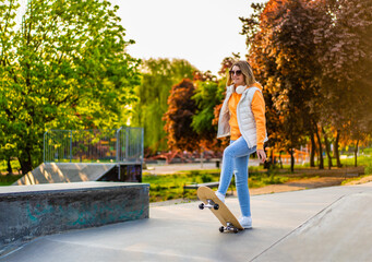 Young woman walking with skateboard in skate park
