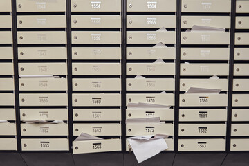 Mail boxes with overflowing documents and bills. Mailboxes with letters in the entrance of an apartment building