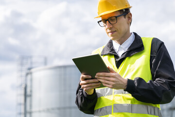 Engineer with digital tablet on a background of gas tanks.	