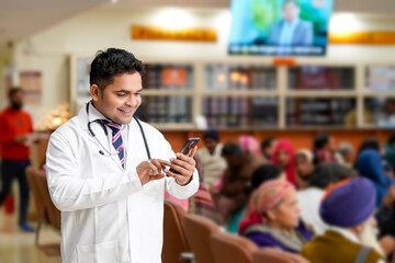 Indian male doctor using smartphone at hospital.