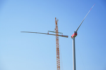 Installing a wind turbine, crane is lifting the second blade to install it to the rotor hub on the...