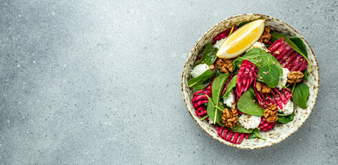 Vegetable salad of beet, baby spinach, nuts and cheese on a light background, Long banner format. top view