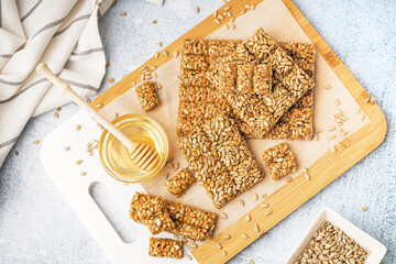 Wooden board with tasty kozinaki and bowl of honey on white grunge background