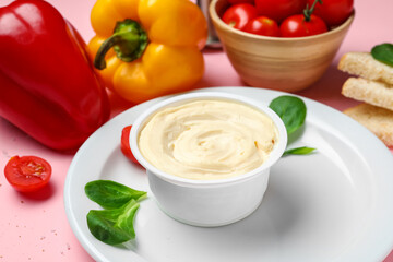 Plate with box of processed cheese, toasts and vegetables on pink background