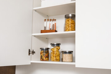 Cupboard with food and spices in light kitchen