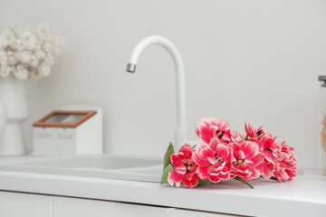 Sink with beautiful tulips in light kitchen, closeup