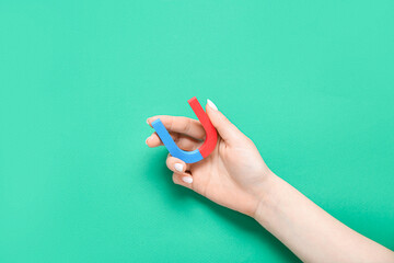 Female hand with mini magnet on green background