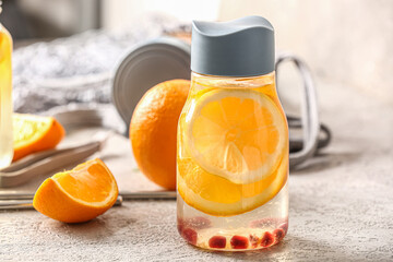Sports bottle of infused water with orange slices on grey table