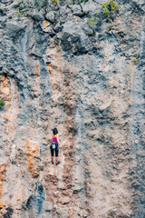Alone woman climbing on a huge cliff in mountains