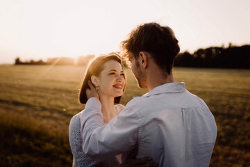 couple in love in a field at sunset on a date in summer. Wedding engagement of a young couple.