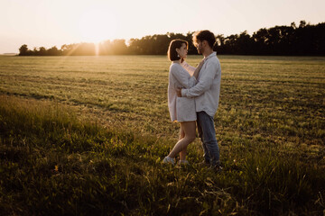 couple in love in a field at sunset on a date in summer. Wedding engagement of a young couple.