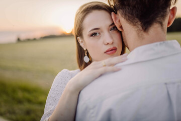couple in love in a field at sunset on a date in summer. Wedding engagement of a young couple.