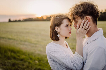 Obraz premium couple in love in a field at sunset on a date in summer. Wedding engagement of a young couple.