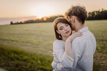 Fototapeta na wymiar couple in love in a field at sunset on a date in summer. Wedding engagement of a young couple.